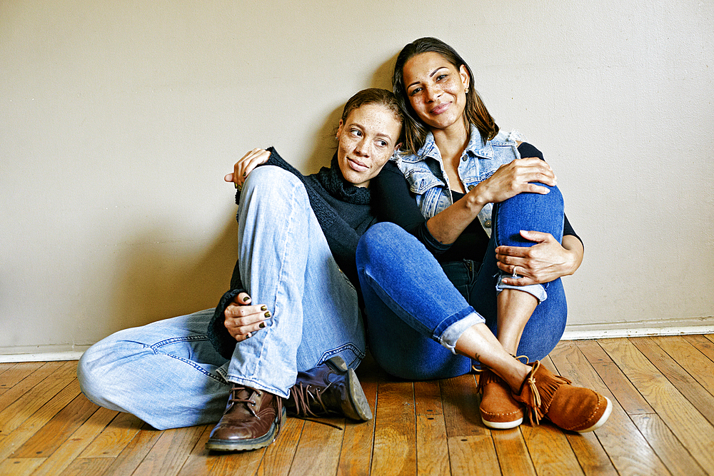 Smiling mixed race women sitting on floor