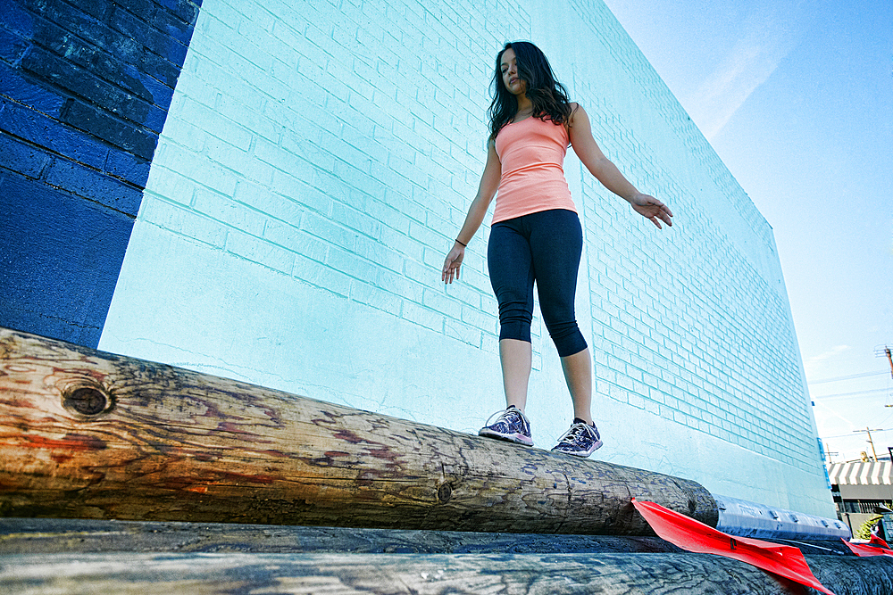 Mixed race woman walking on log