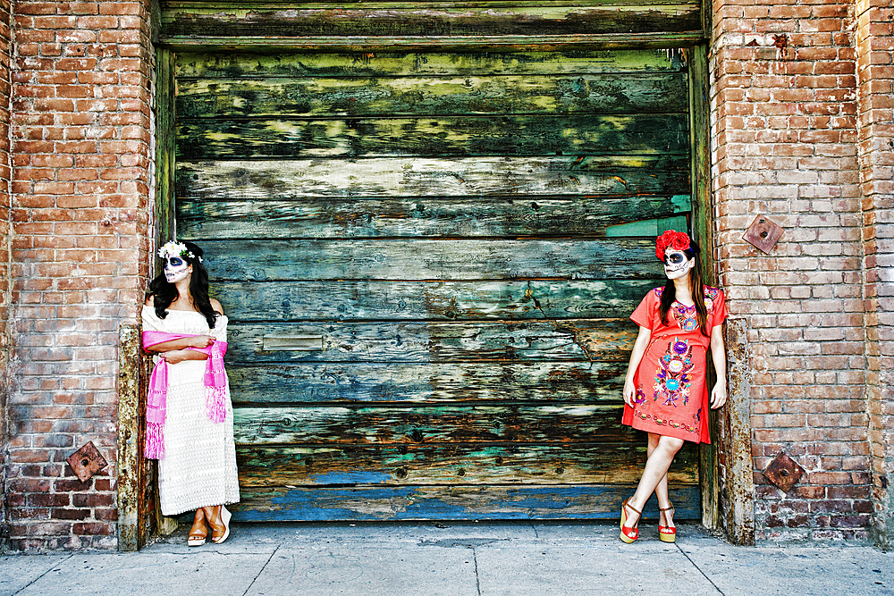 Women leaning on loading dock wearing skull face paint