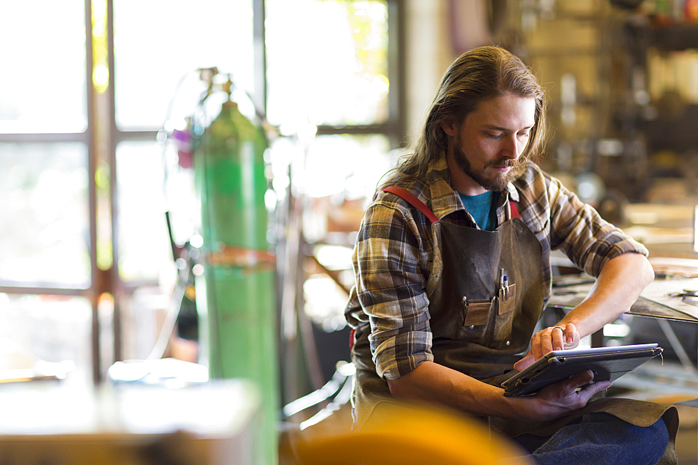 Caucasian man reading a digital tablet in workshop