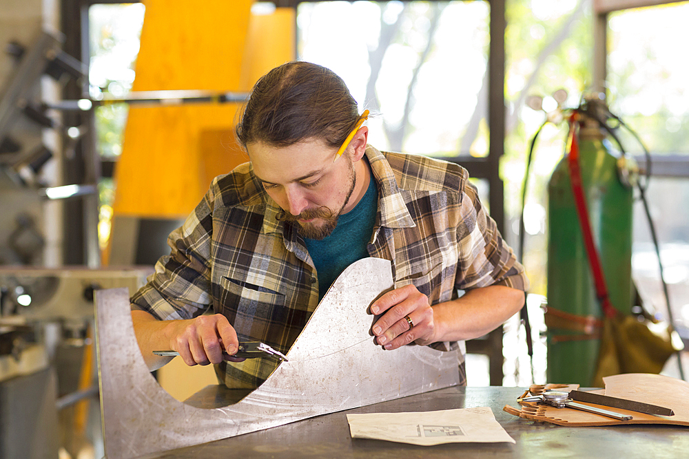 Caucasian man measuring metal with caliper