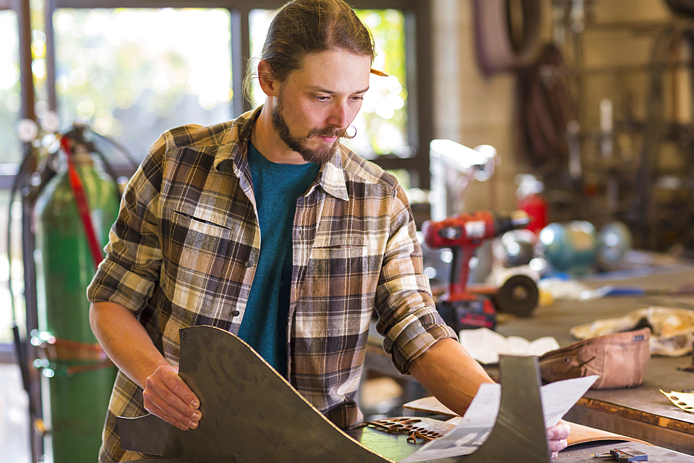 Caucasian man holding metal and reading paperwork