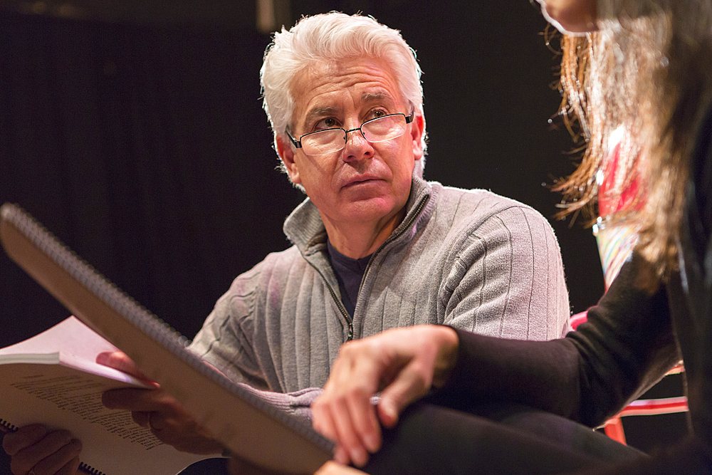 Hispanic man and woman reading scripts in theater