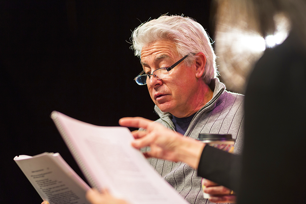 Hispanic man and woman reading scripts in theater