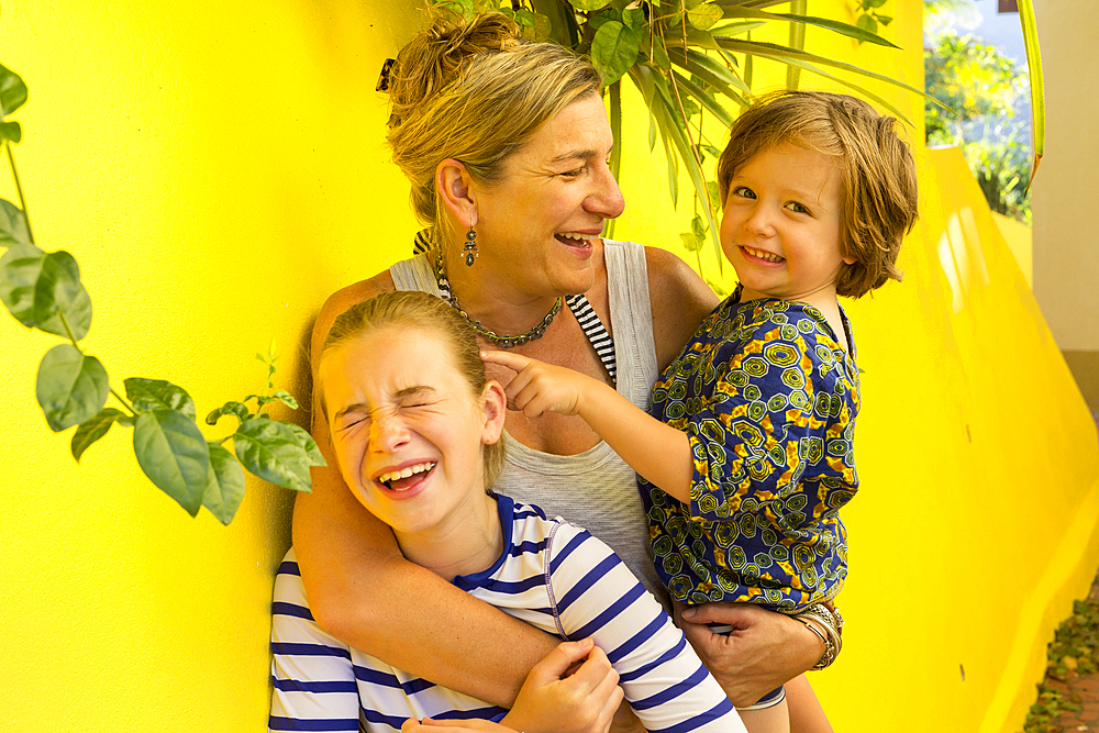 Laughing Caucasian mother hugging son and daughter