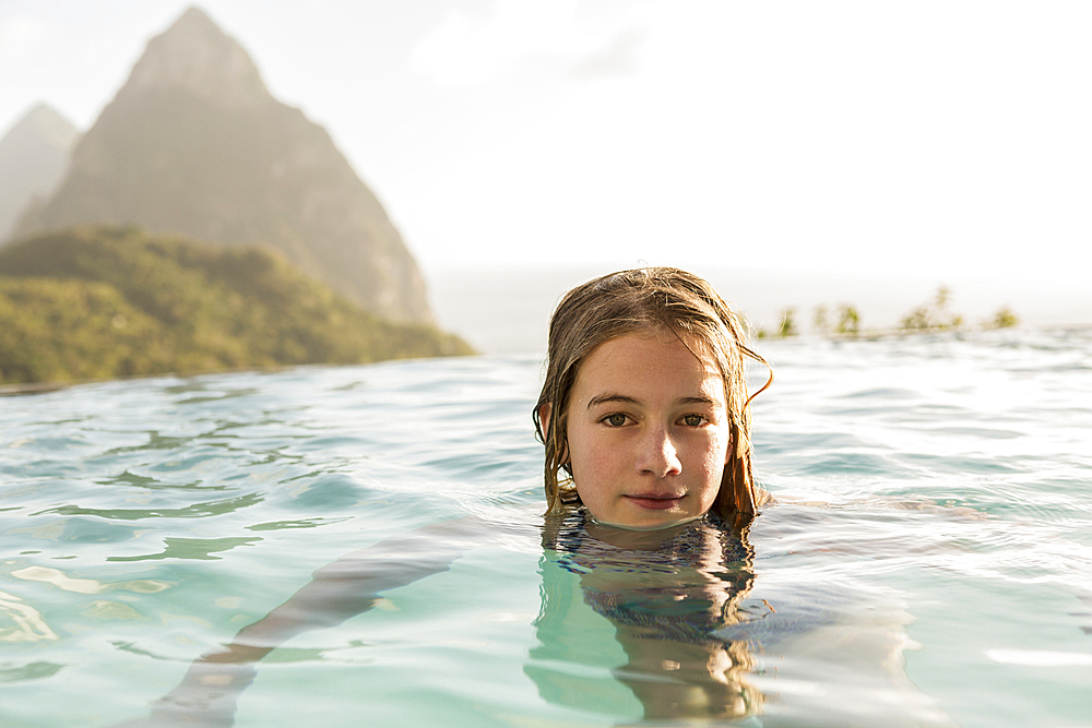 Caucasian girl swimming in infinity pool