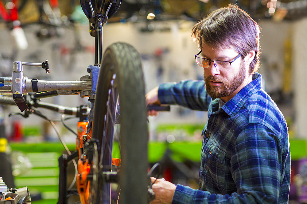 Caucasian man repairing bicycle in shop