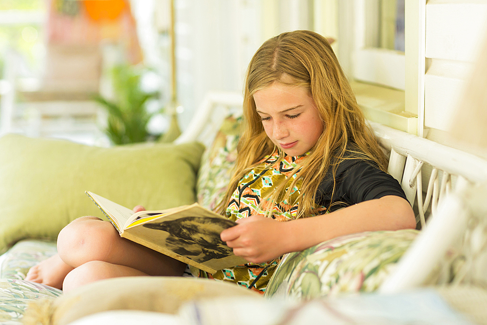 Caucasian girl reading book on sofa