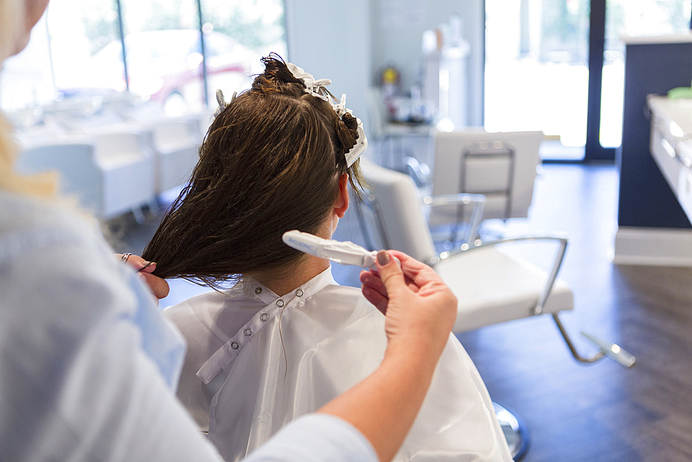 Stylist styling hair of woman