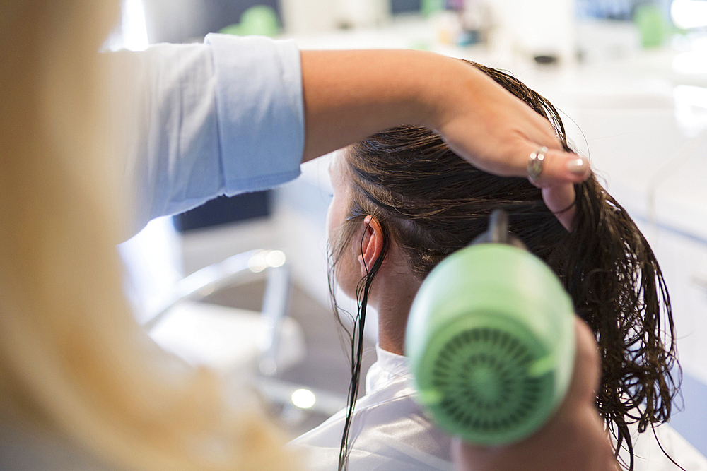 Stylist drying hair of woman