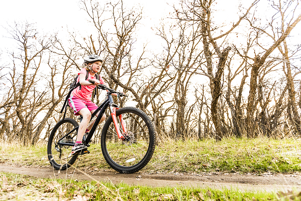 Caucasian girl riding bicycle on forest path