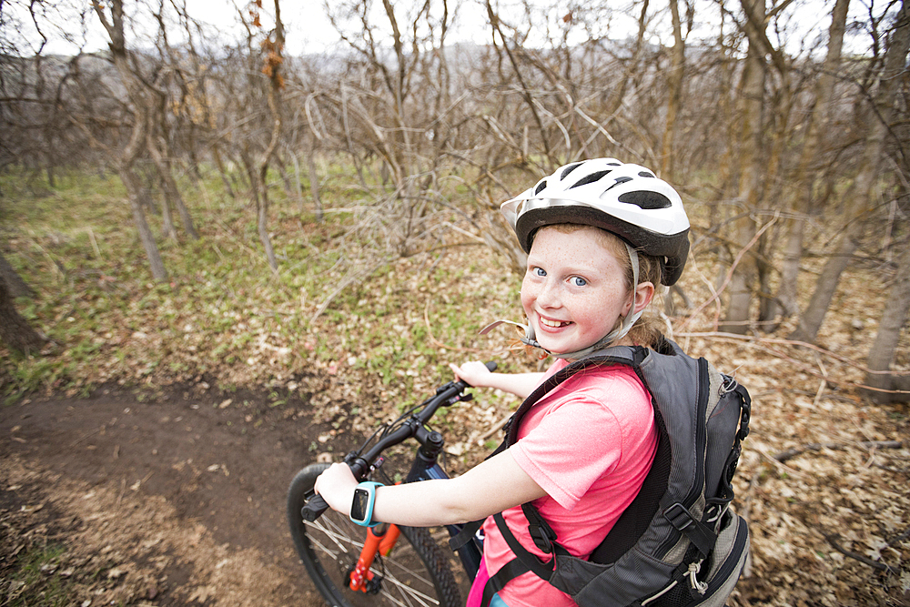 Caucasian girl riding bicycle on forest path