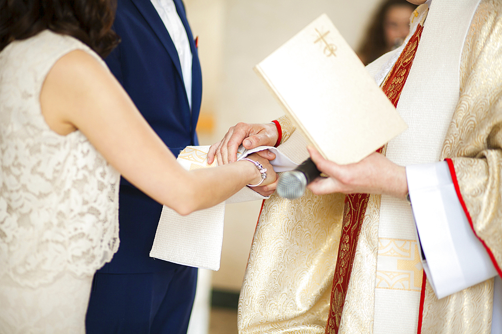 Priest and couple joining hands in wedding