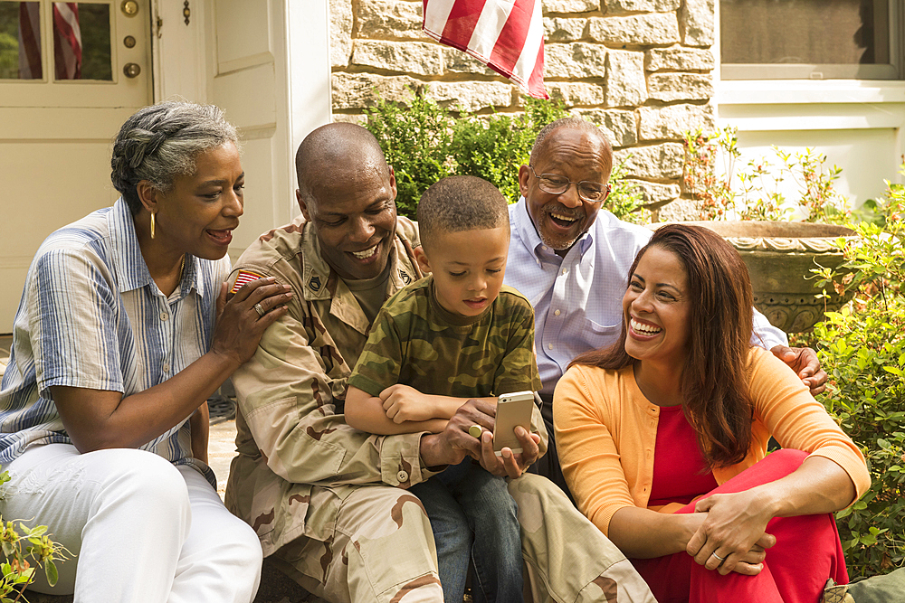 Soldier and multi-generation family looking down at cell phone