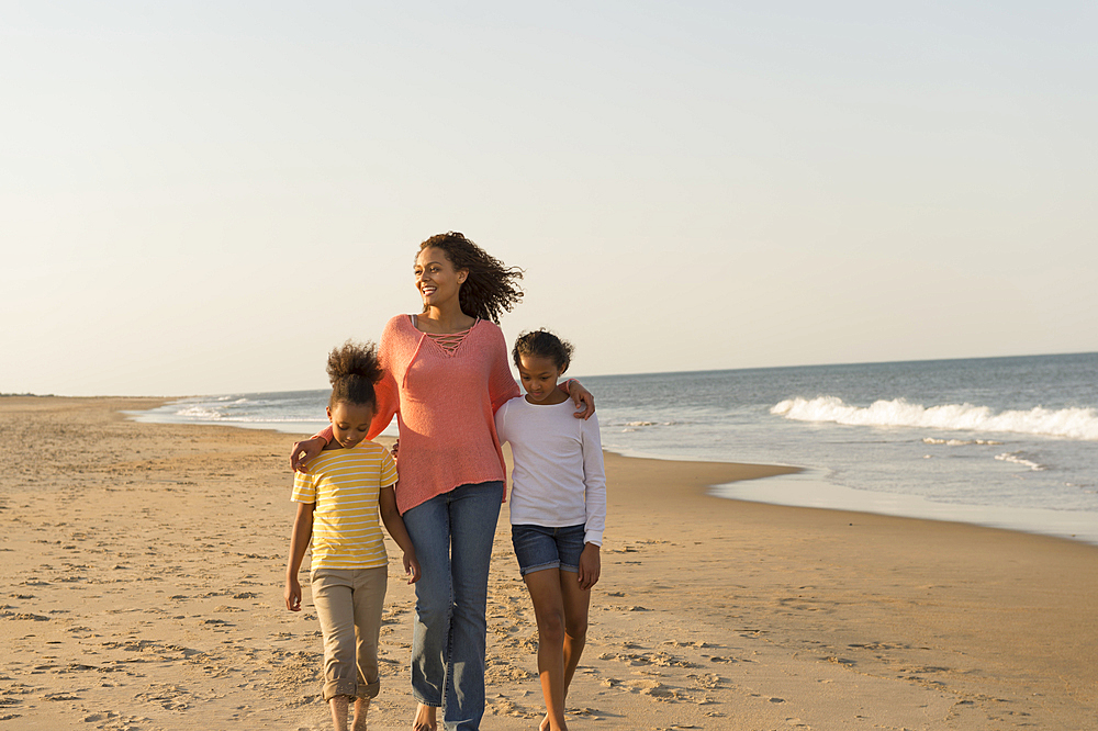 Mother and daughters walking on beach