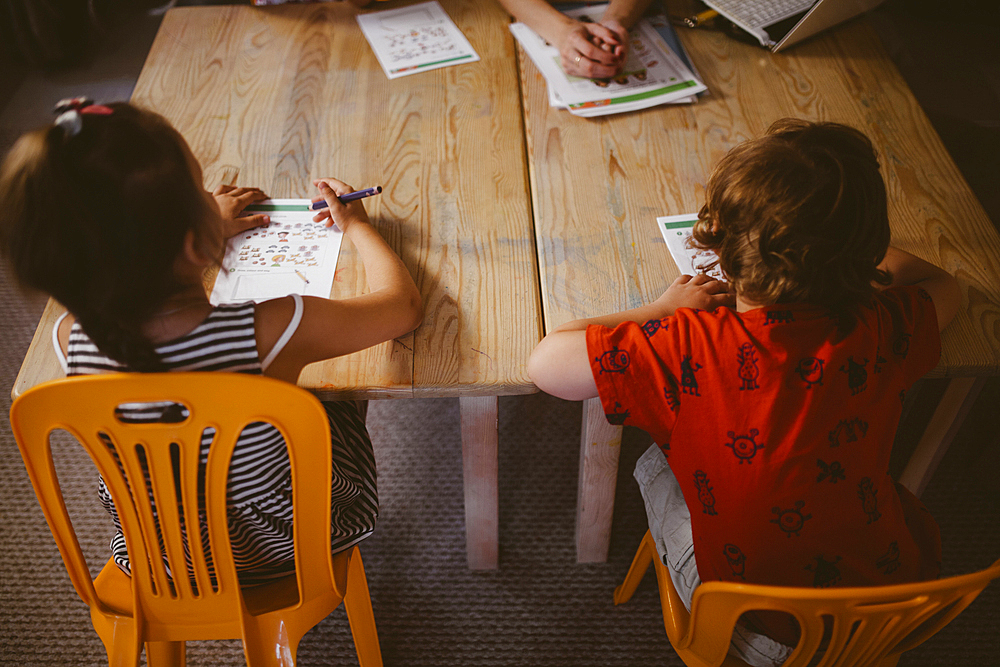 Caucasian boy and girl sitting at table coloring