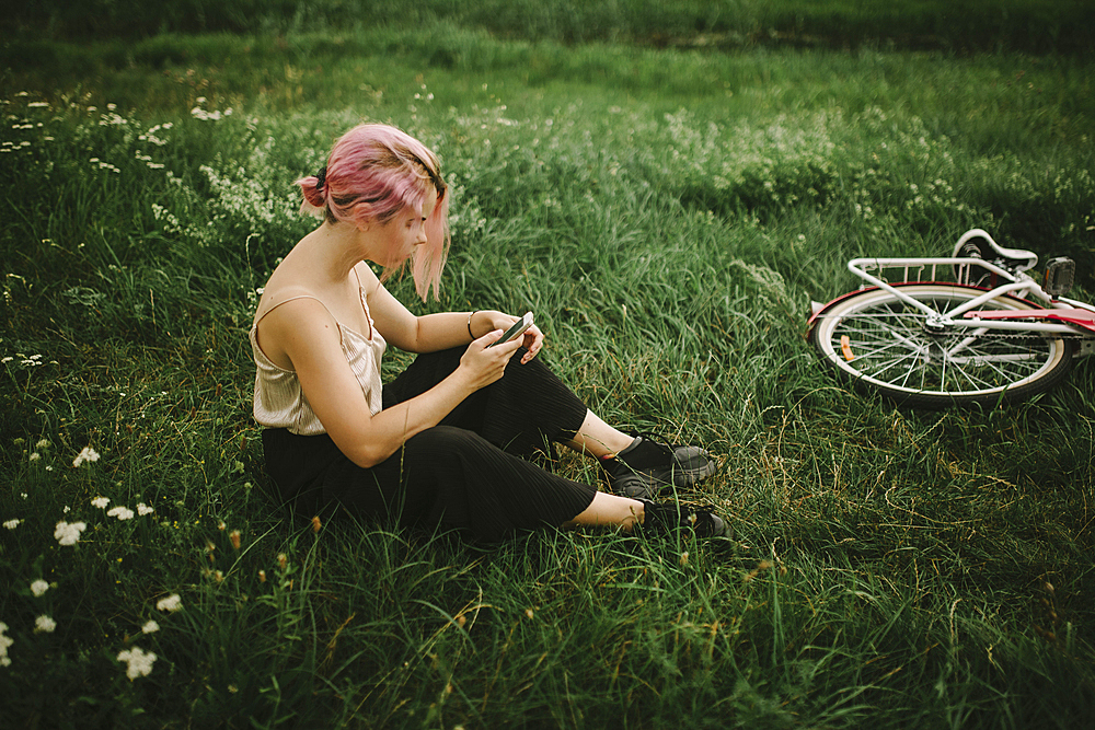 Caucasian woman sitting infield texting on cell phone