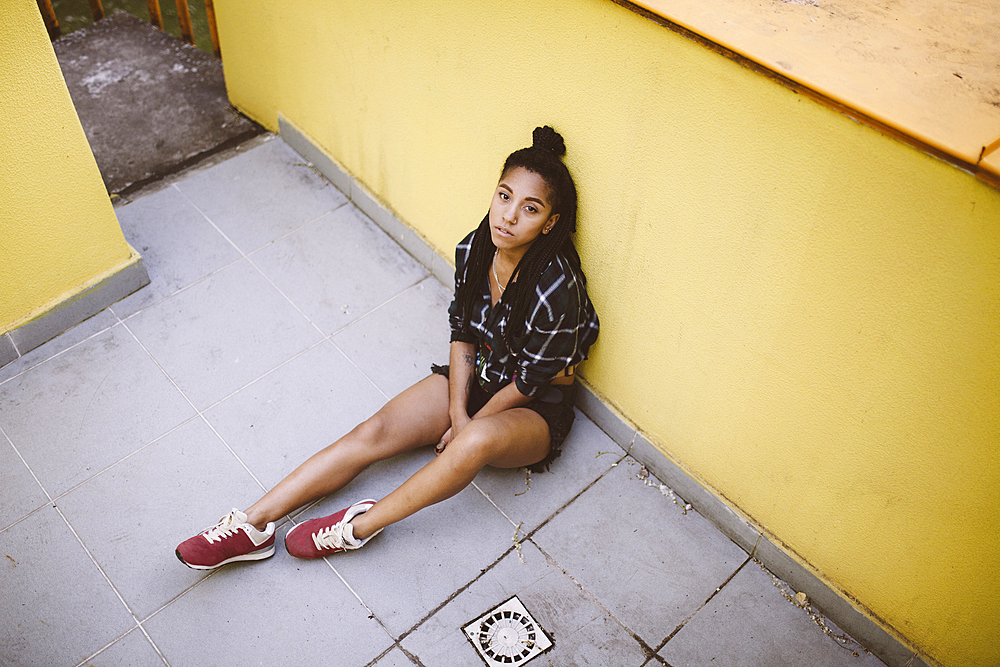 Portrait of serious African American woman sitting on sidewalk