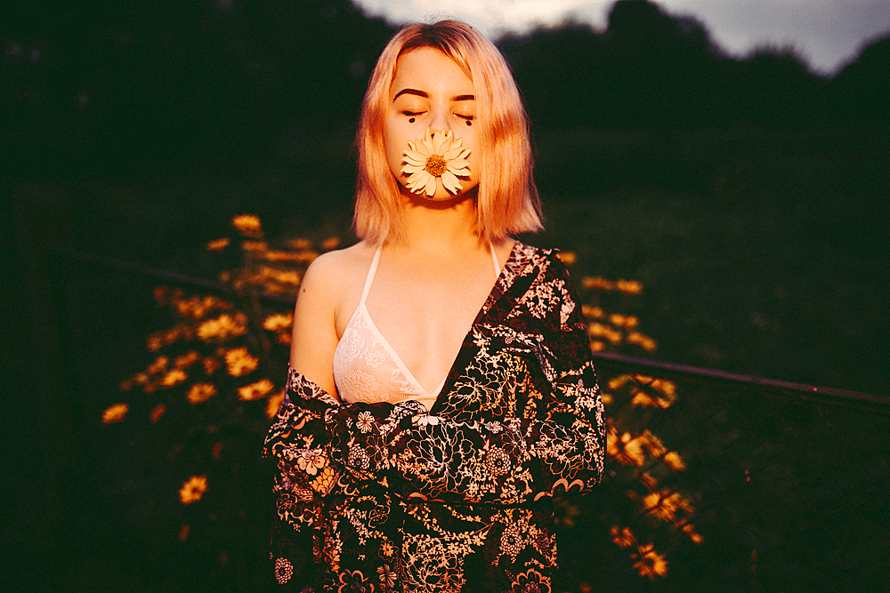 Caucasian woman posing with flower in mouth