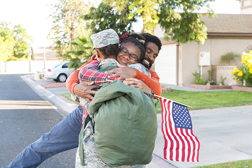 Black woman soldier hugging man and daughter