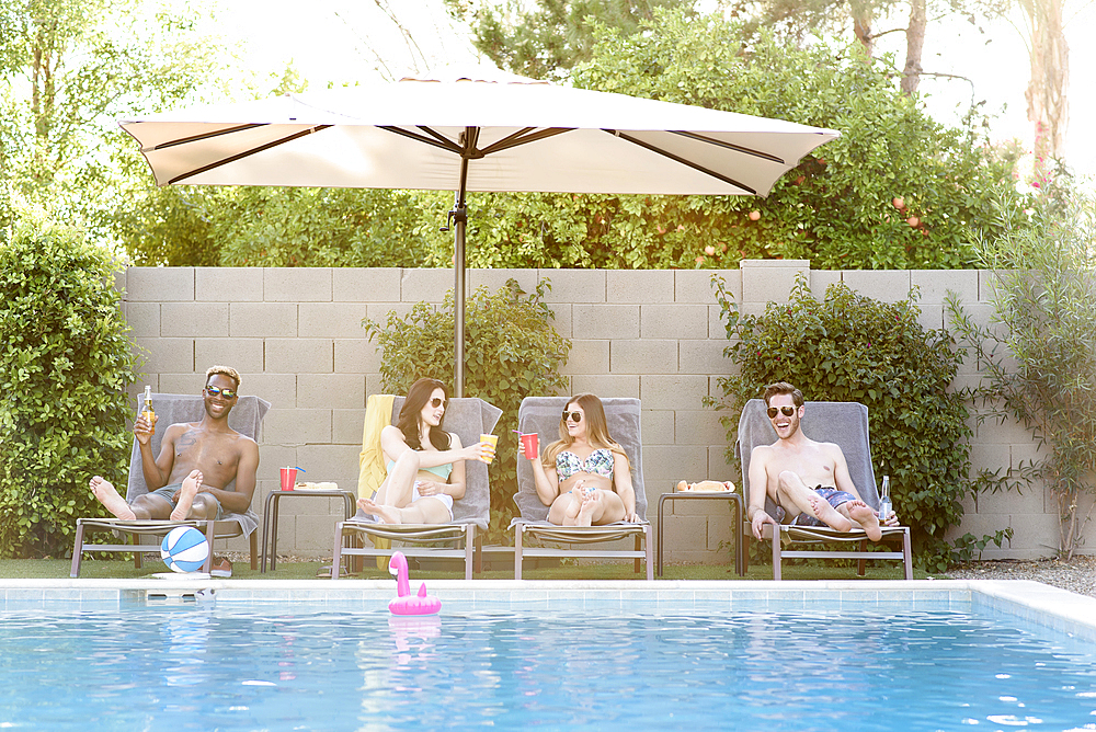 Friends relaxing with beer and cocktails at swimming pool