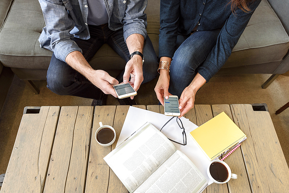 Hands of Caucasian couple texting on cell phones