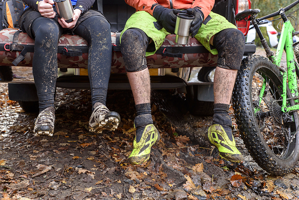 Legs of Caucasian couple sitting in pickup truck near bicycle