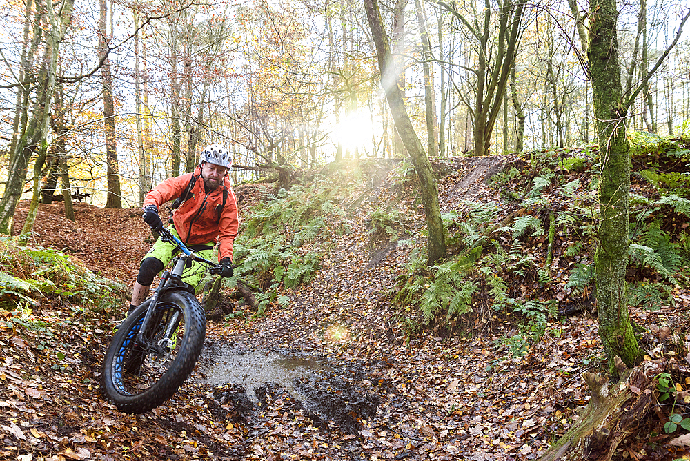 Caucasian man steering bicycle around mud puddle