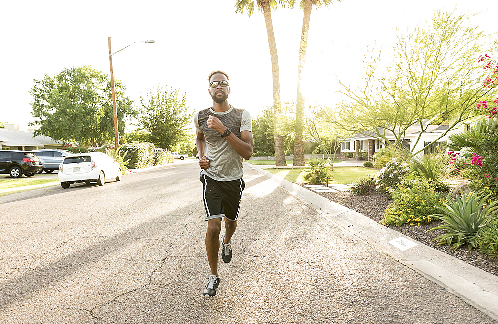 Black man running on street in neighborhood