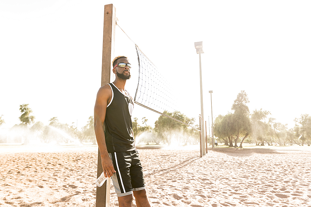 Black man leaning on beach volleyball net