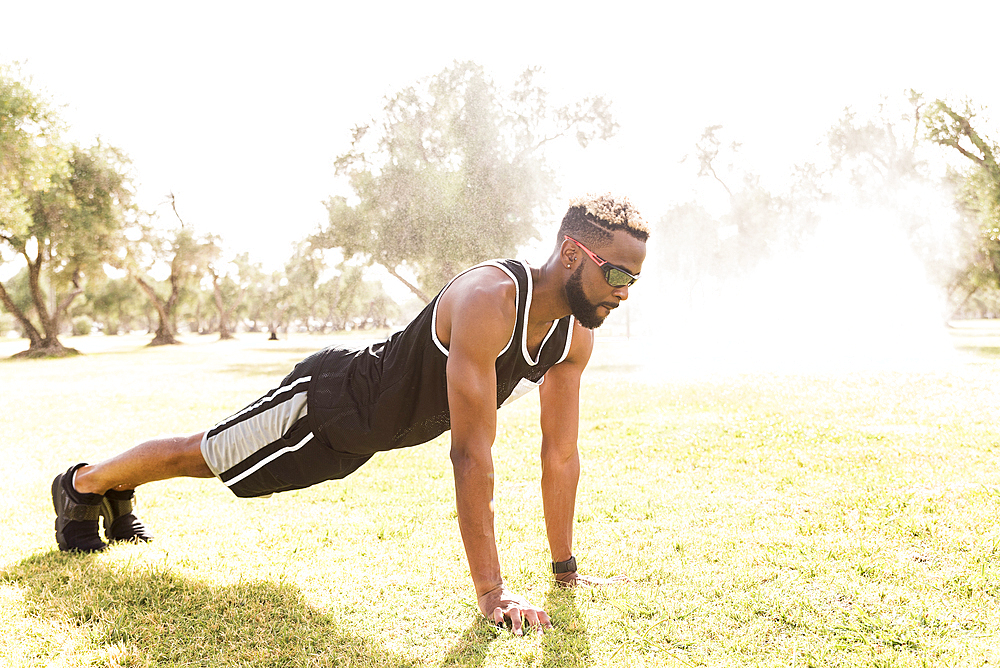 Black man doing push-ups in park