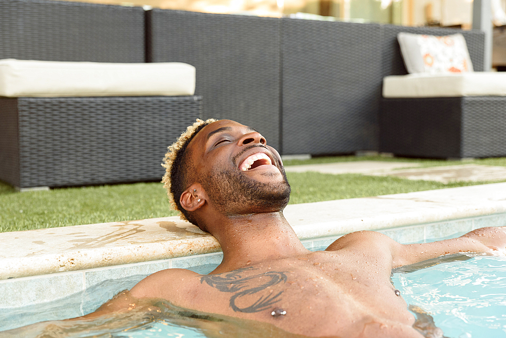 Smiling Black man relaxing in swimming pool