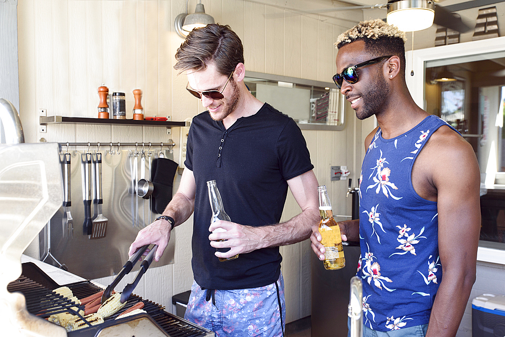 Men drinking beer and cooking on grille outdoors