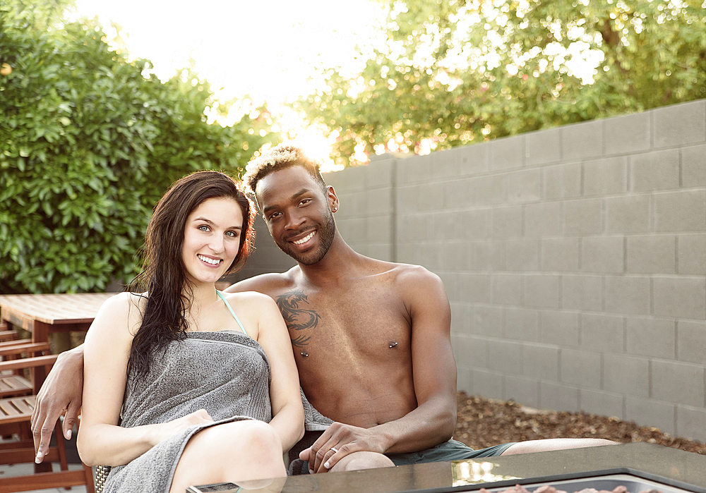 Portrait of smiling couple wrapped in towels near fire pit