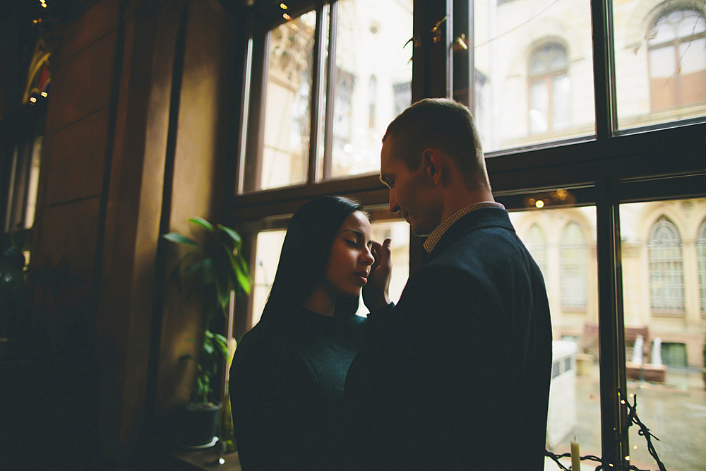 Caucasian couple embracing near window