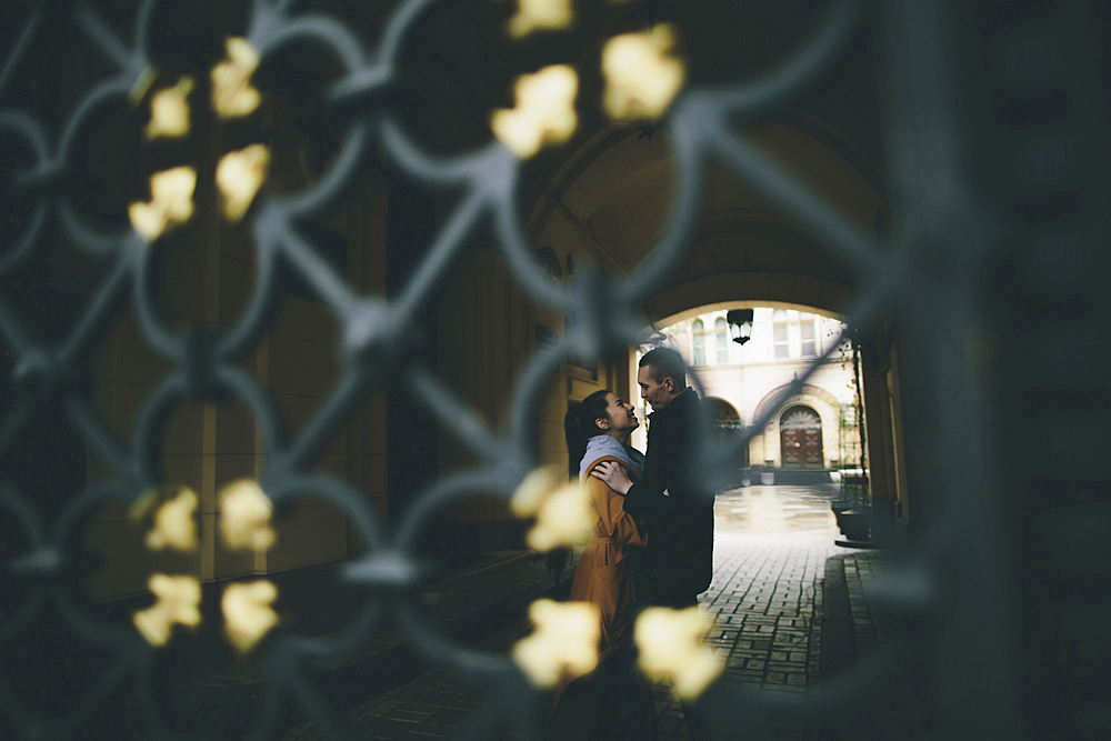 Caucasian couple embracing in street behind gate