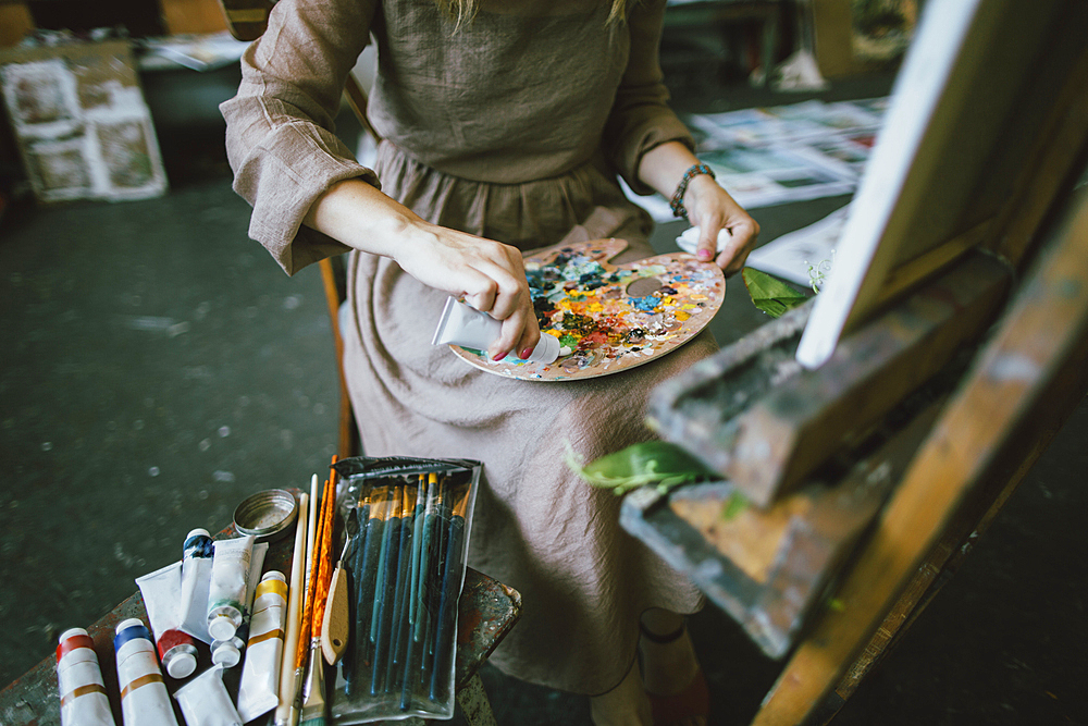 Caucasian woman squeezing paint onto palette