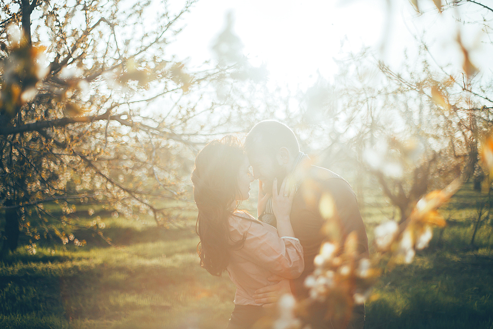 Caucasian couple rubbing noses near trees