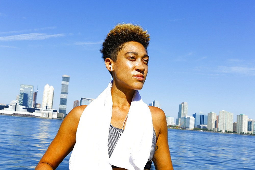 Mixed race woman listening to earbuds at waterfront