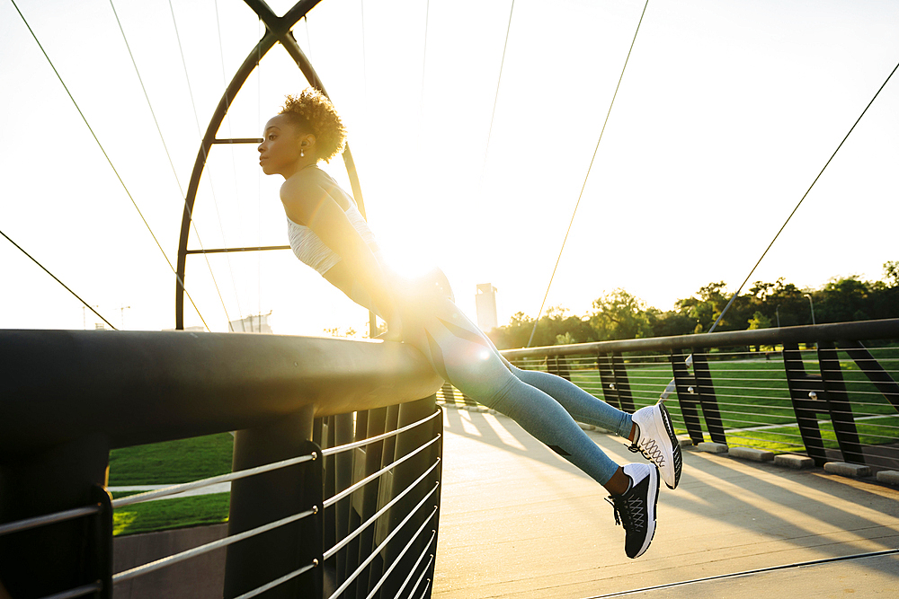 Curious mixed race woman leaning on bridge railing