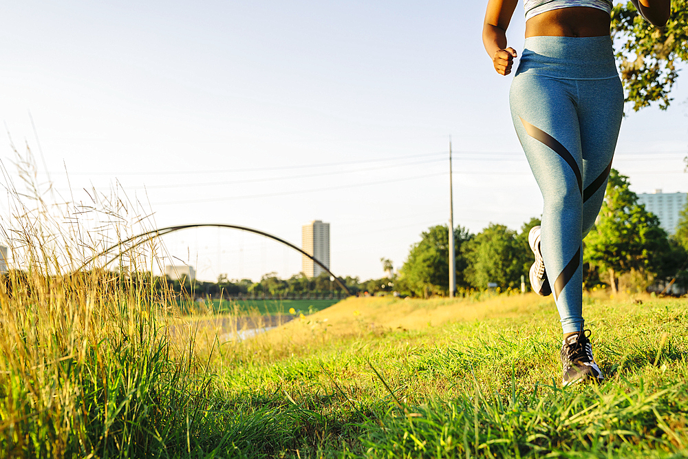 Legs of mixed race woman running in grass near waterfront