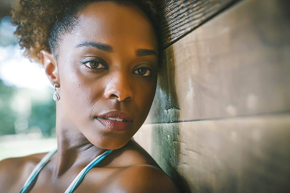 Close up portrait of serious mixed race woman leaning on wall