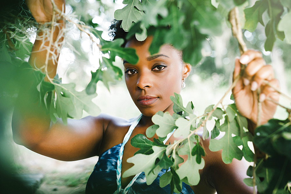 Portrait of serious mixed race woman holding tree branches