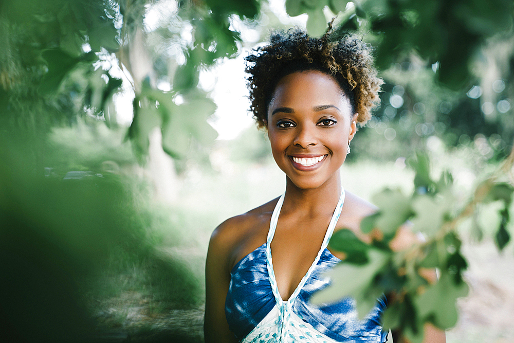 Portrait of smiling mixed race woman near tree