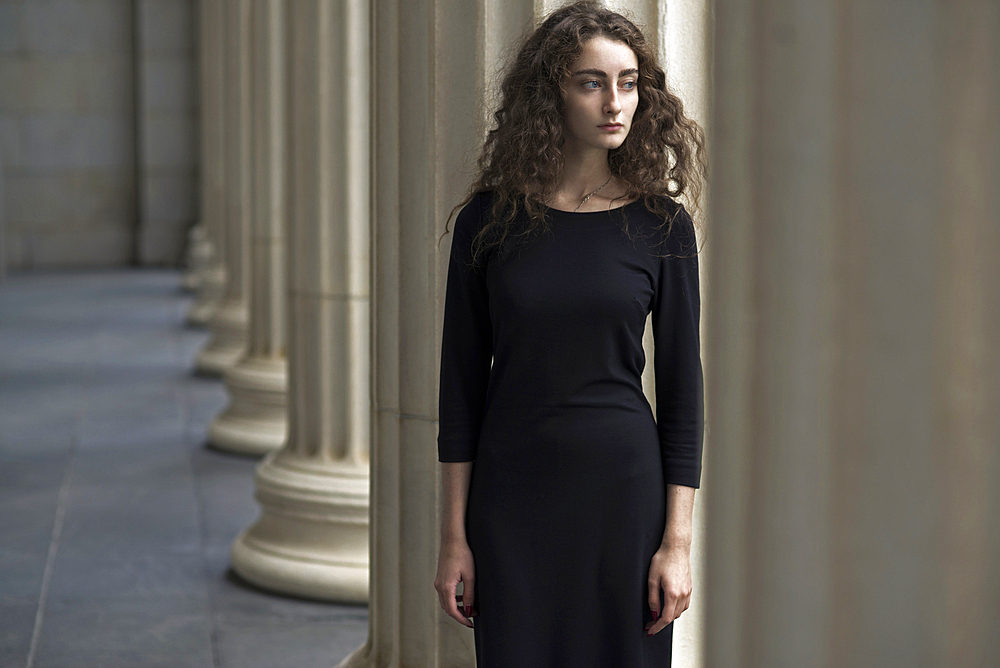 Serious Caucasian woman standing near pillars