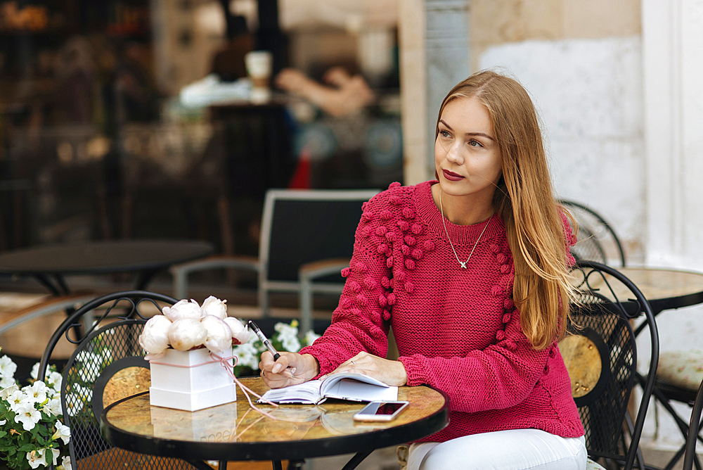 Caucasian woman sitting at table writing in journal