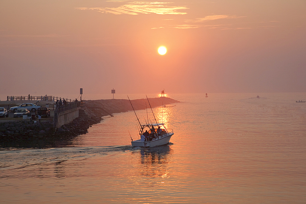 People on boat and at waterfront at sunset