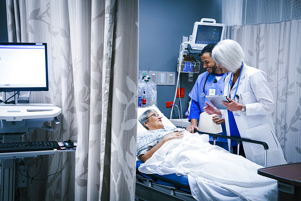 Doctor and nurse talking with patient in hospital bed