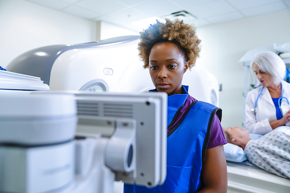 Technician preparing scanner for doctor comforting patient