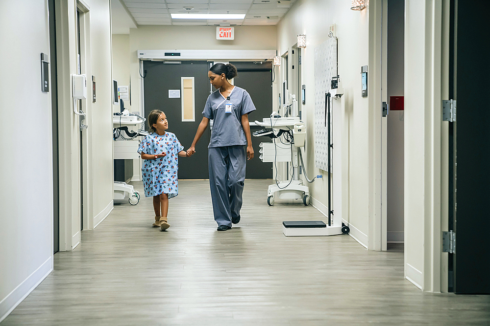 Nurse holding hands with girl in hospital